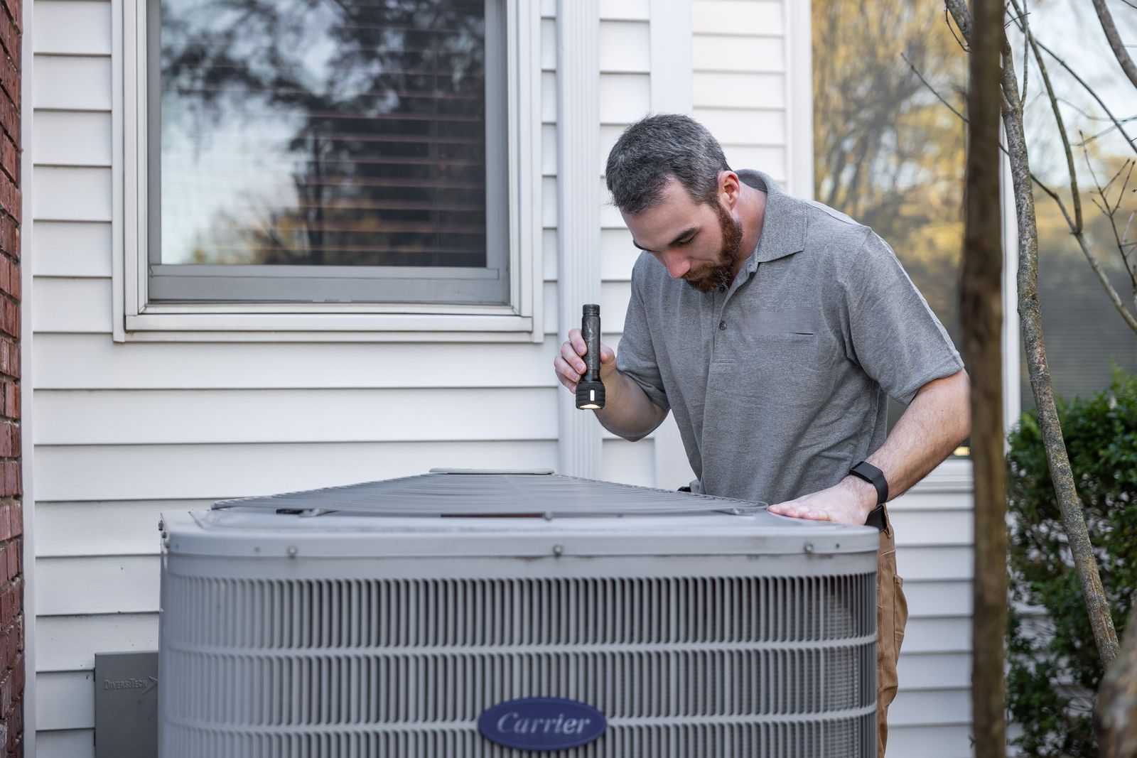 HVAC technician inspecting an outdoor air conditioning unit during a maintenance visit